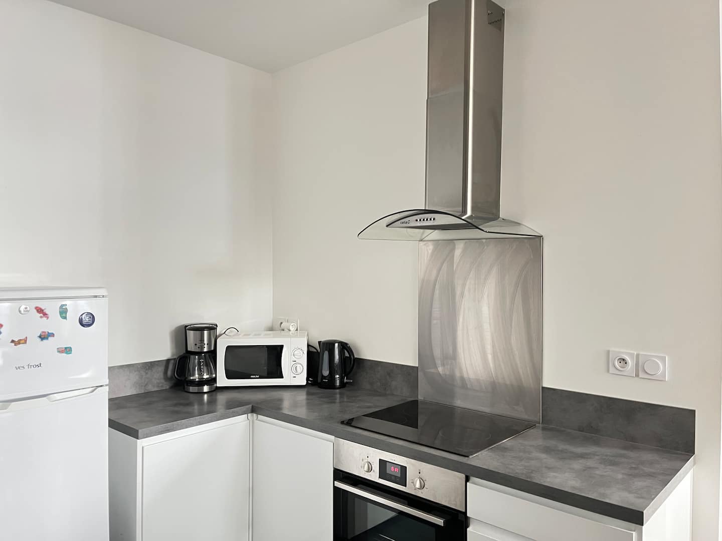 Cuisine équipée avec plaques de cuisson, hotte, four, micro-ondes et réfrigérateur