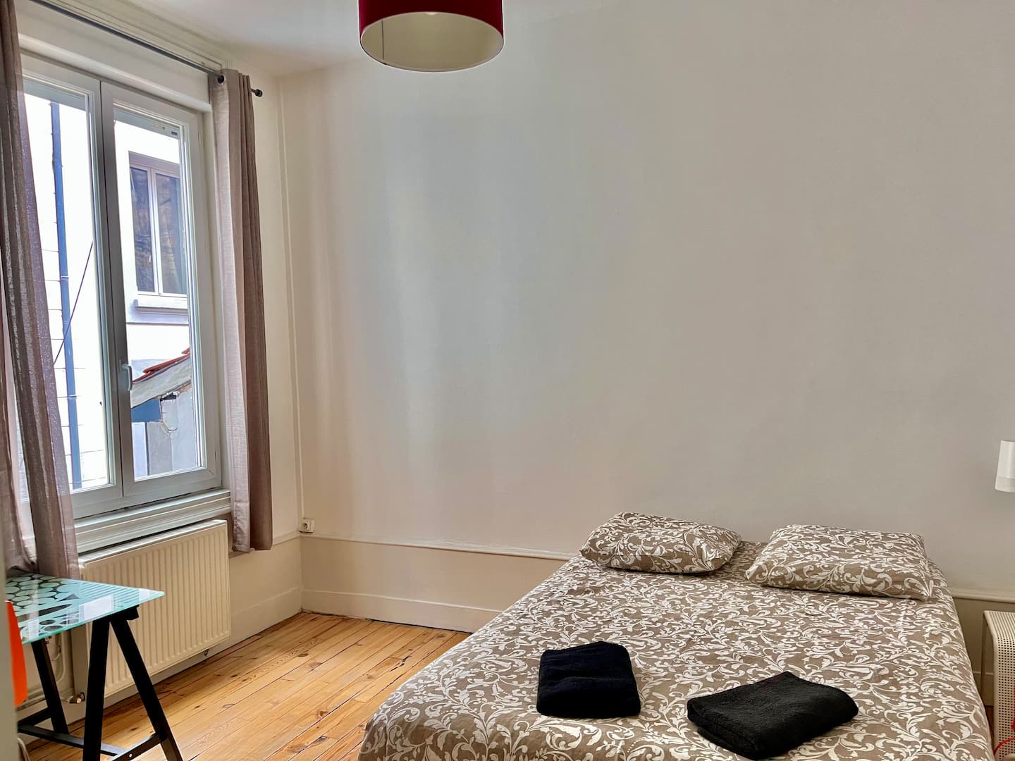 Chambre 1 avec lit double à couvre-lit à motifs, serviettes pliées et grande fenêtre